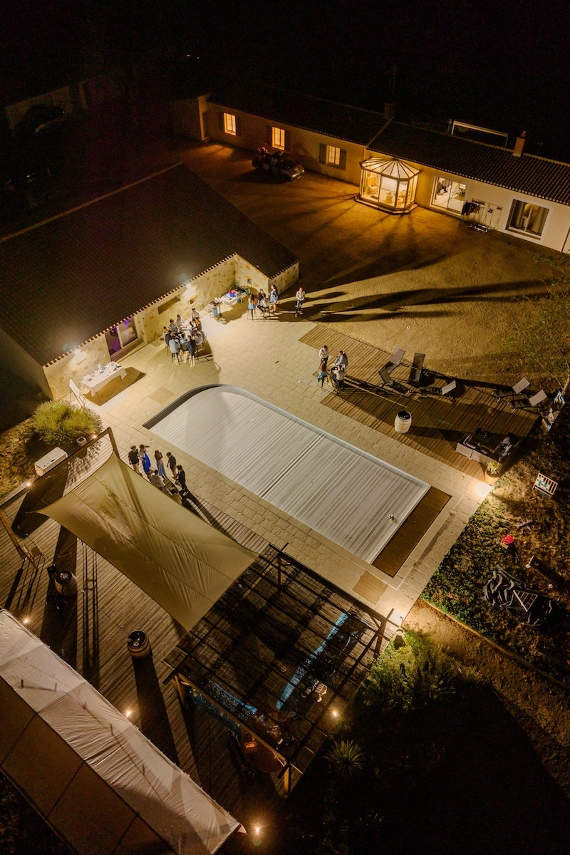 Vue aérienne de nuit du Domaine du Chêne Vert, gîte de 15 personnes avec piscine et terrasse éclairées lors d'une soirée de mariage en Vendée