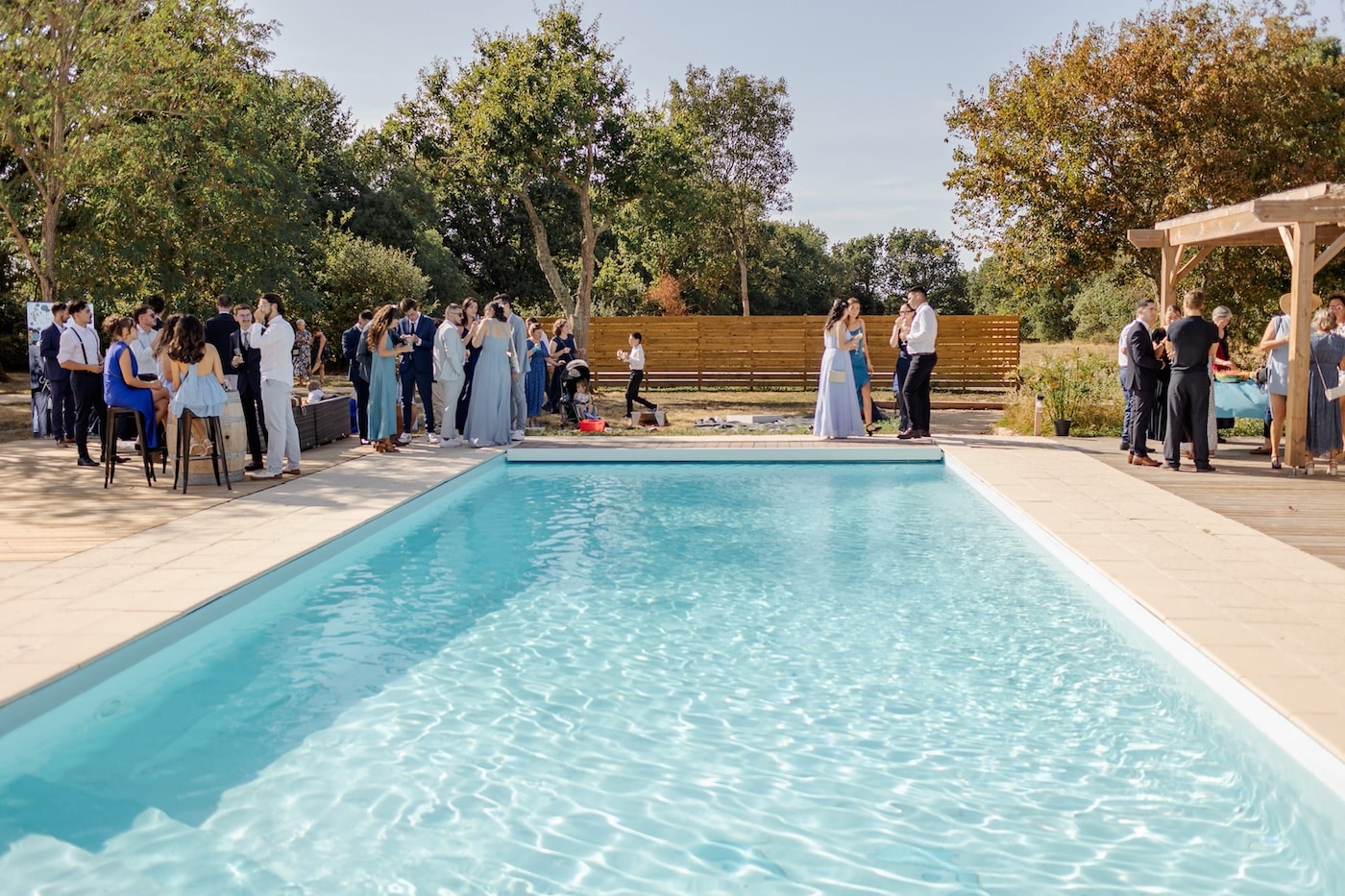 Invités d'un mariage réunis autour de la piscine chauffée du gîte de groupe Domaine du Chêne Vert en Vendée